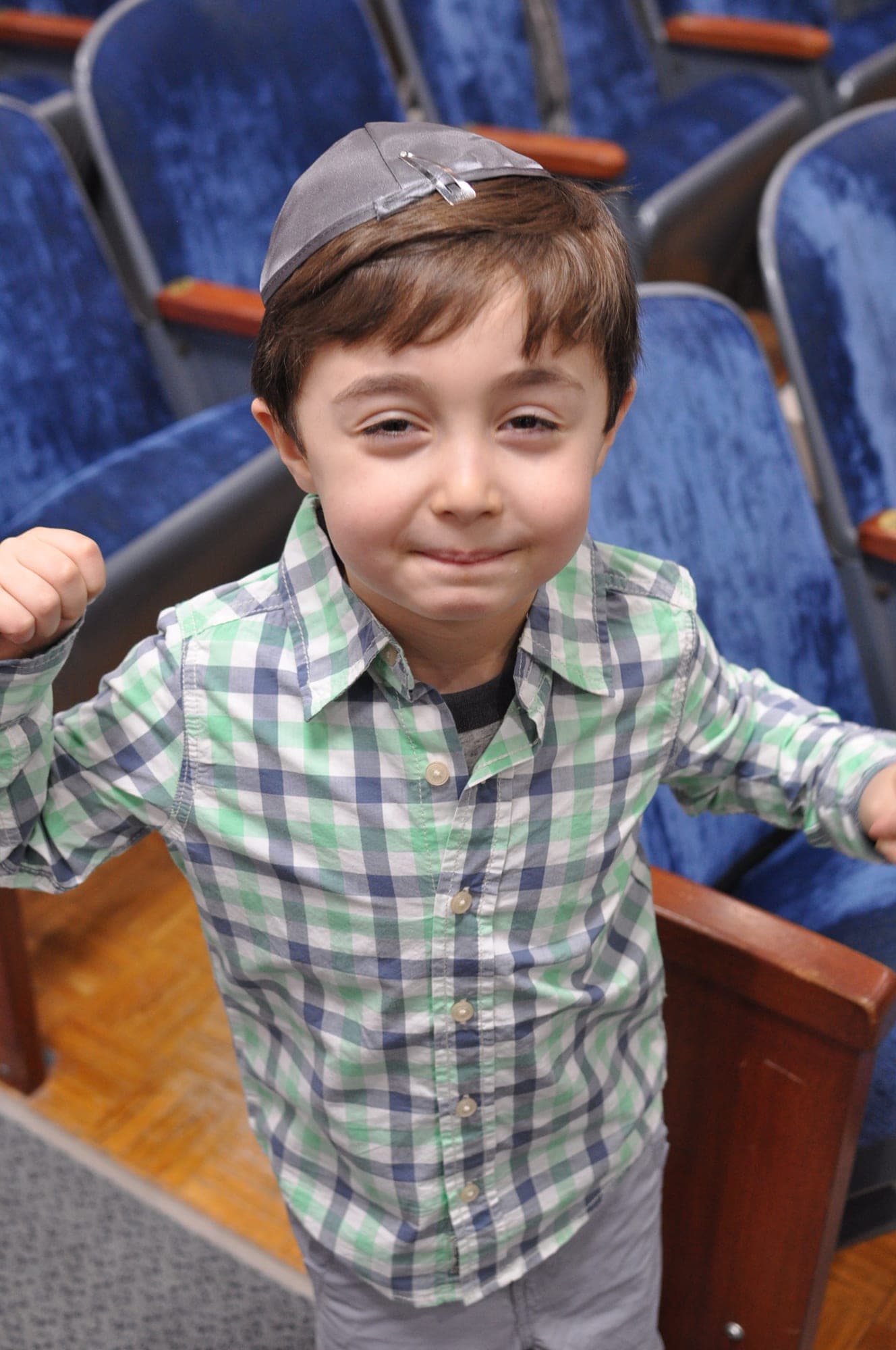 Bar mitzvah boy cheering in the synagogue with his kippah on