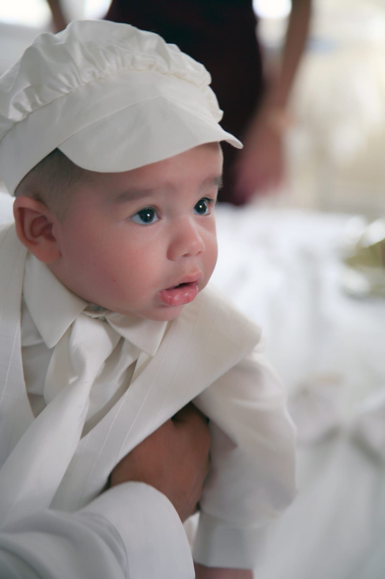 Baby in a white christening cap and gown