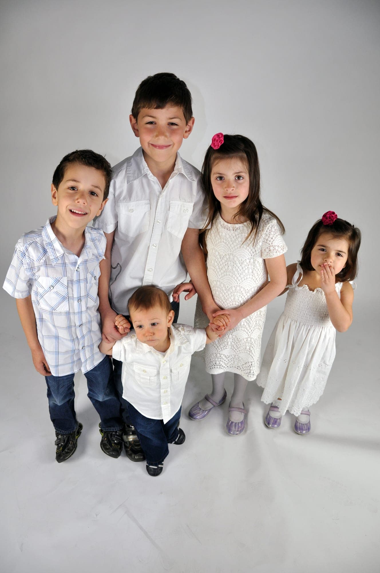 Five siblings photographed full length on a white studio backdrop