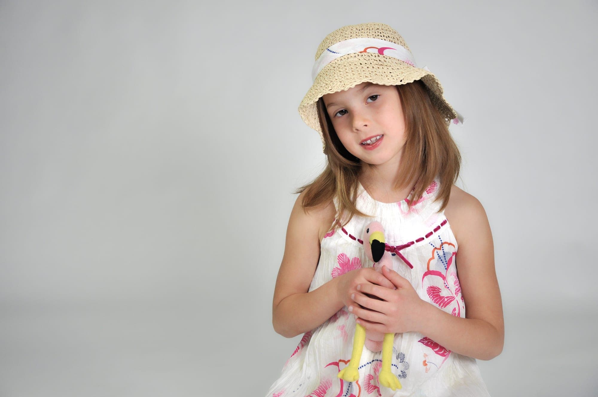 Girl in a straw hat holding a flower in the studio