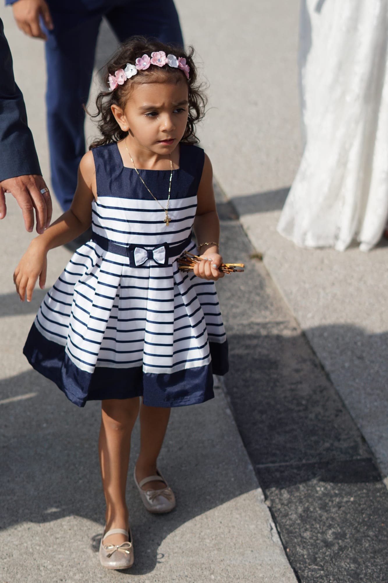 Little girl in a navy striped dress walking with a flower crown