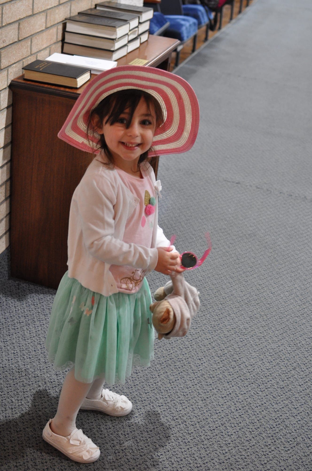 Young girl in a striped sun hat twirling indoors