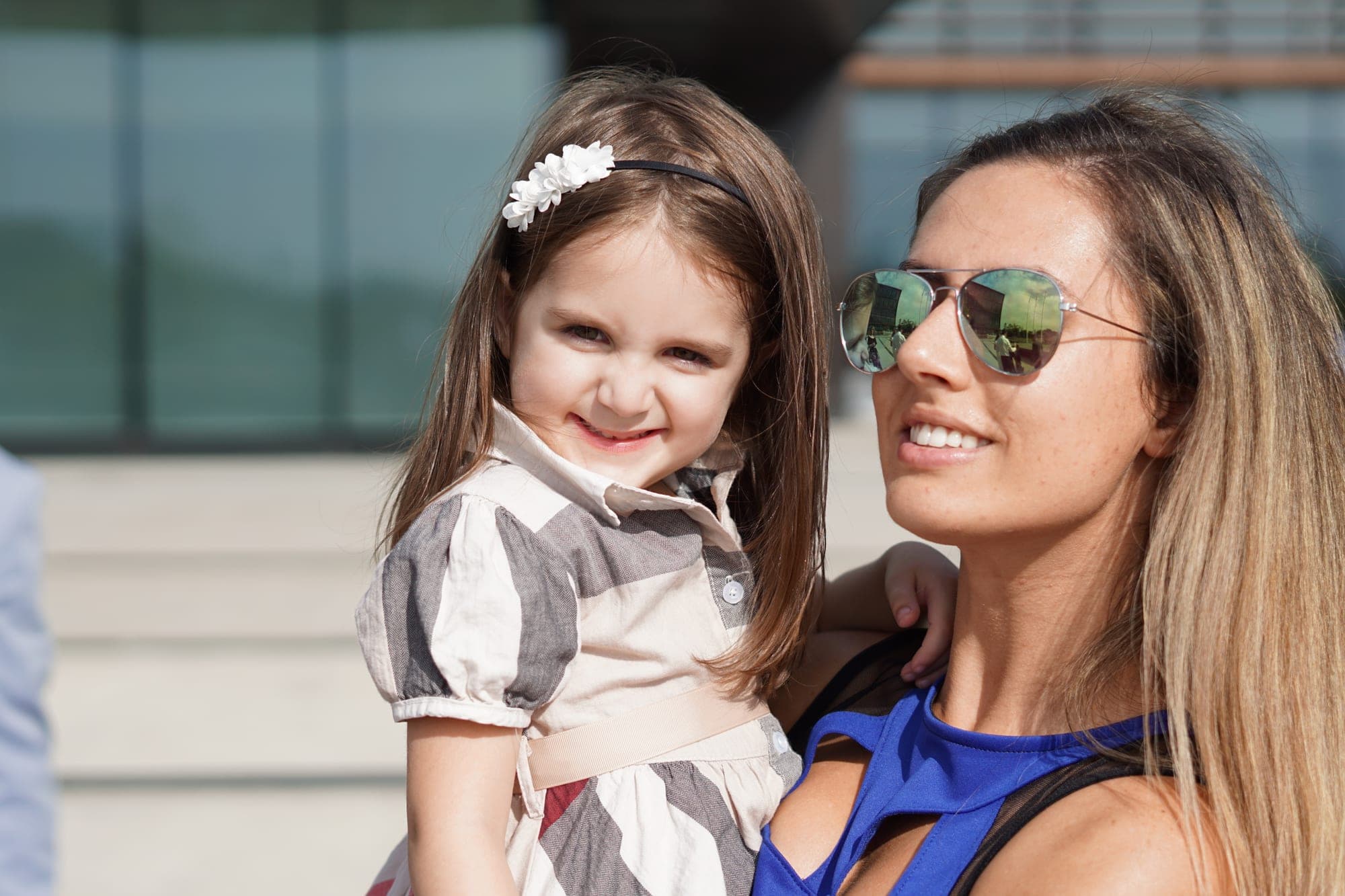 Mother in sunglasses holding her daughter on a summer afternoon