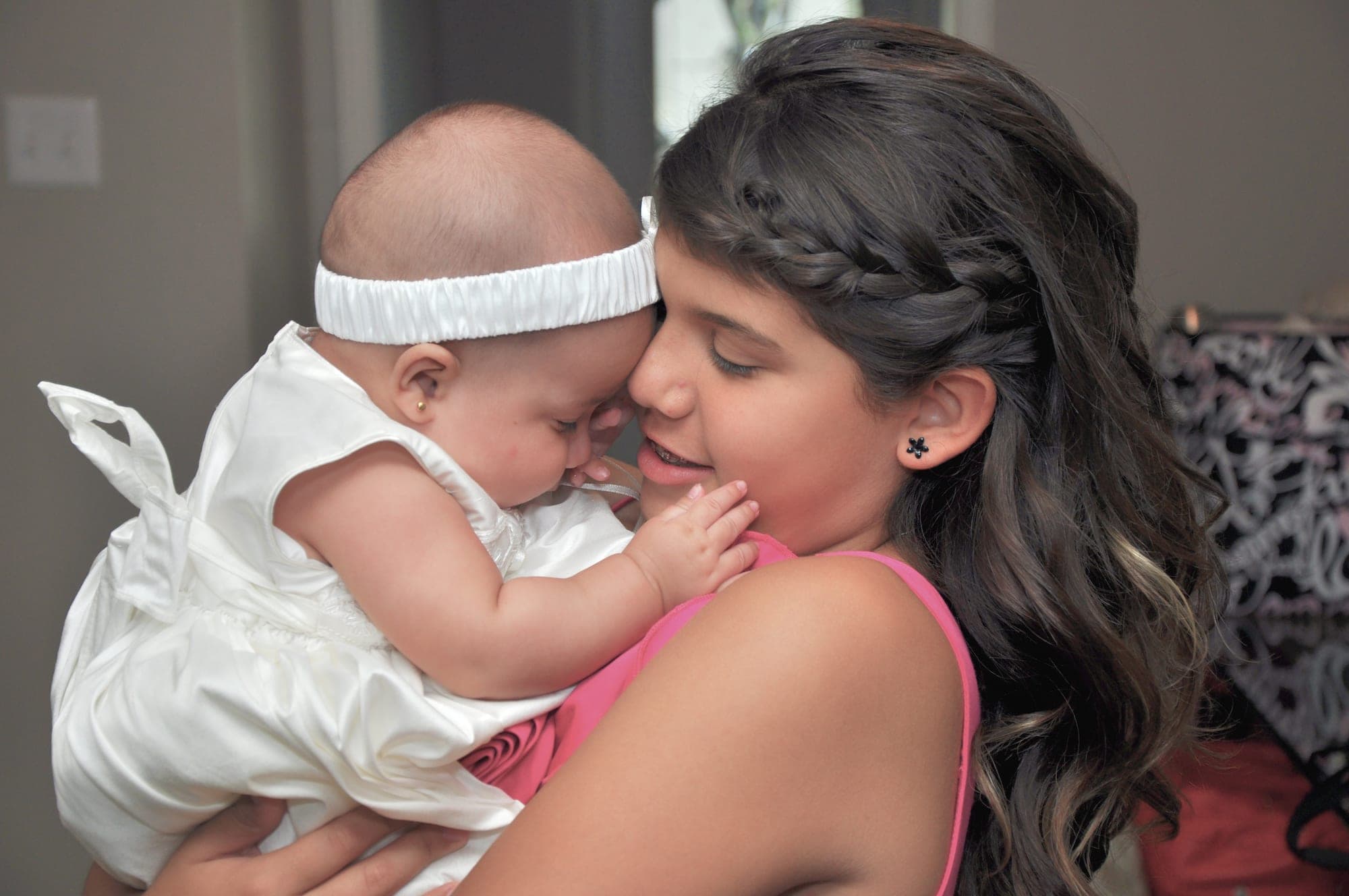 Teenage girl holding her newborn sister close