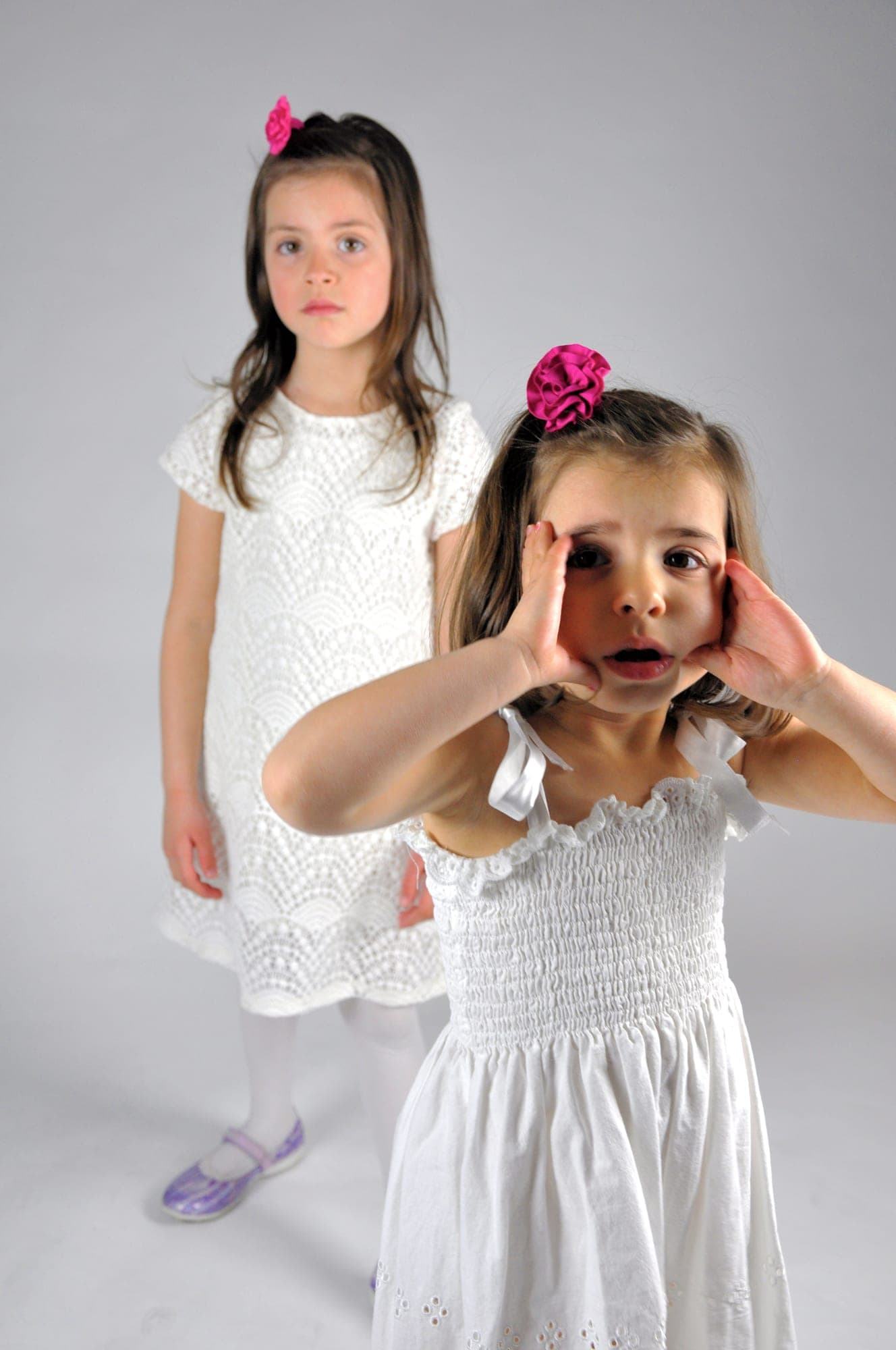 Two young sisters being playful in a white studio