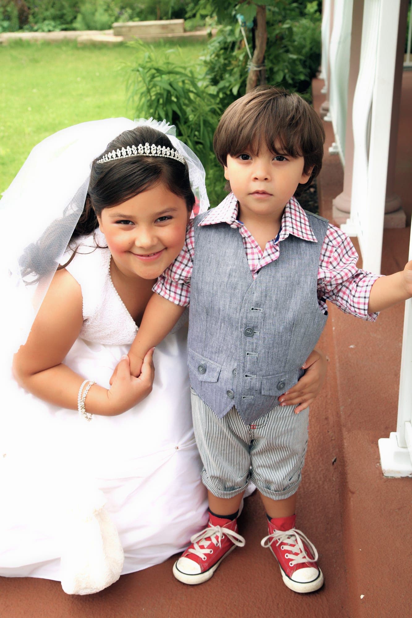 Two children in communion outfits standing together outdoors