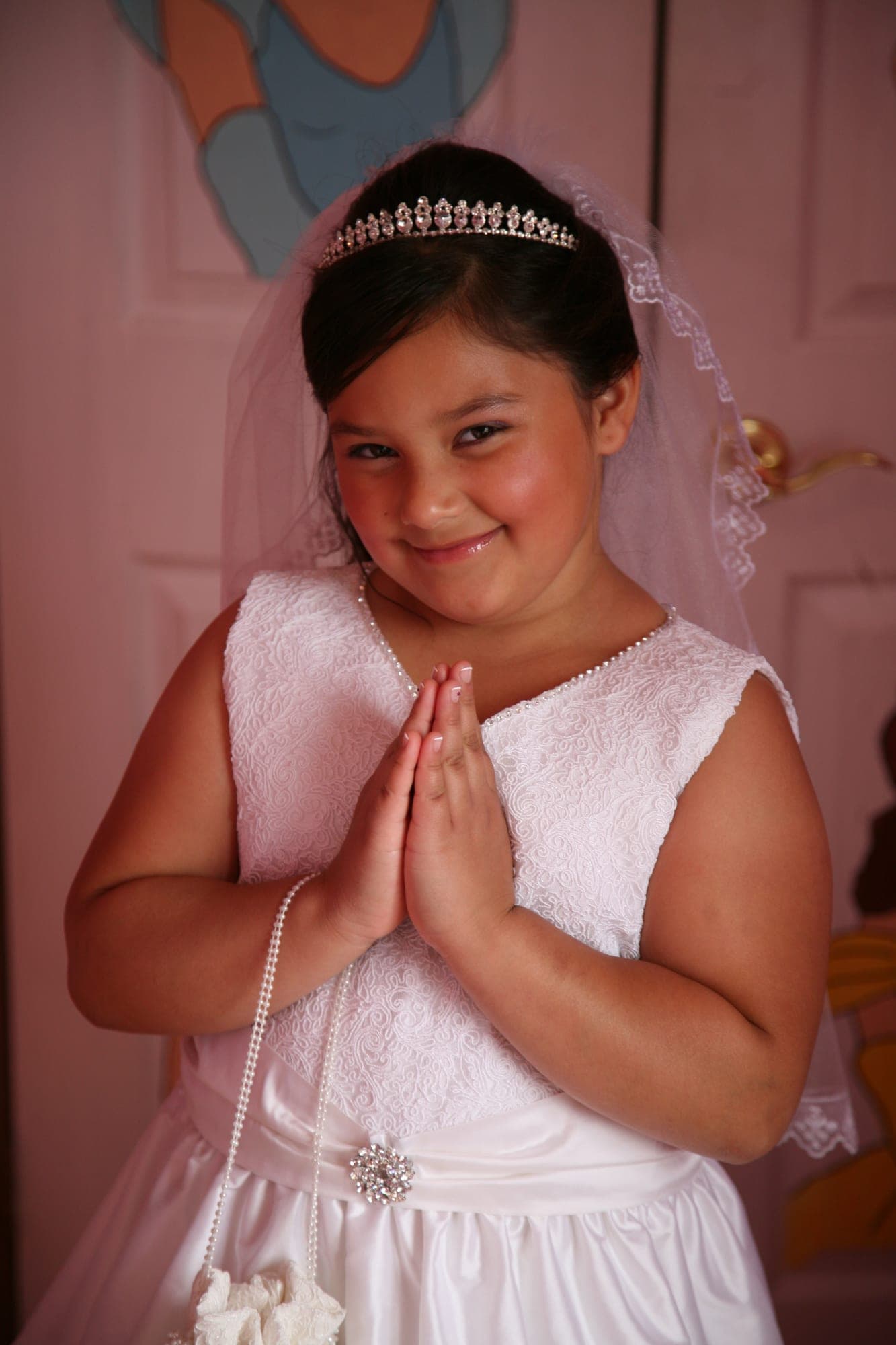 Girl in a communion dress with her hands pressed in prayer