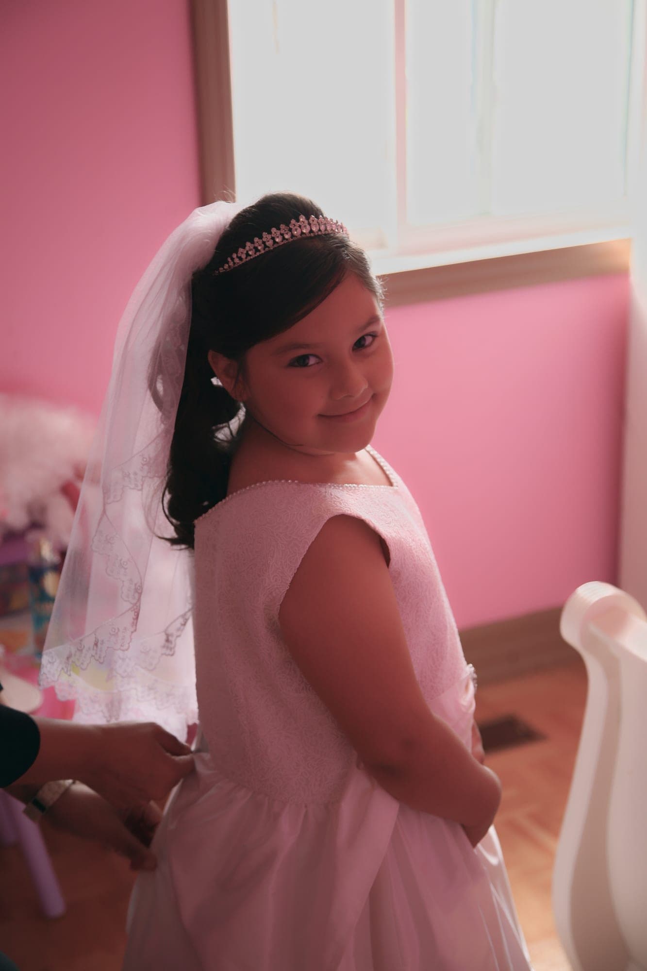 Girl in a white first communion dress and veil at home