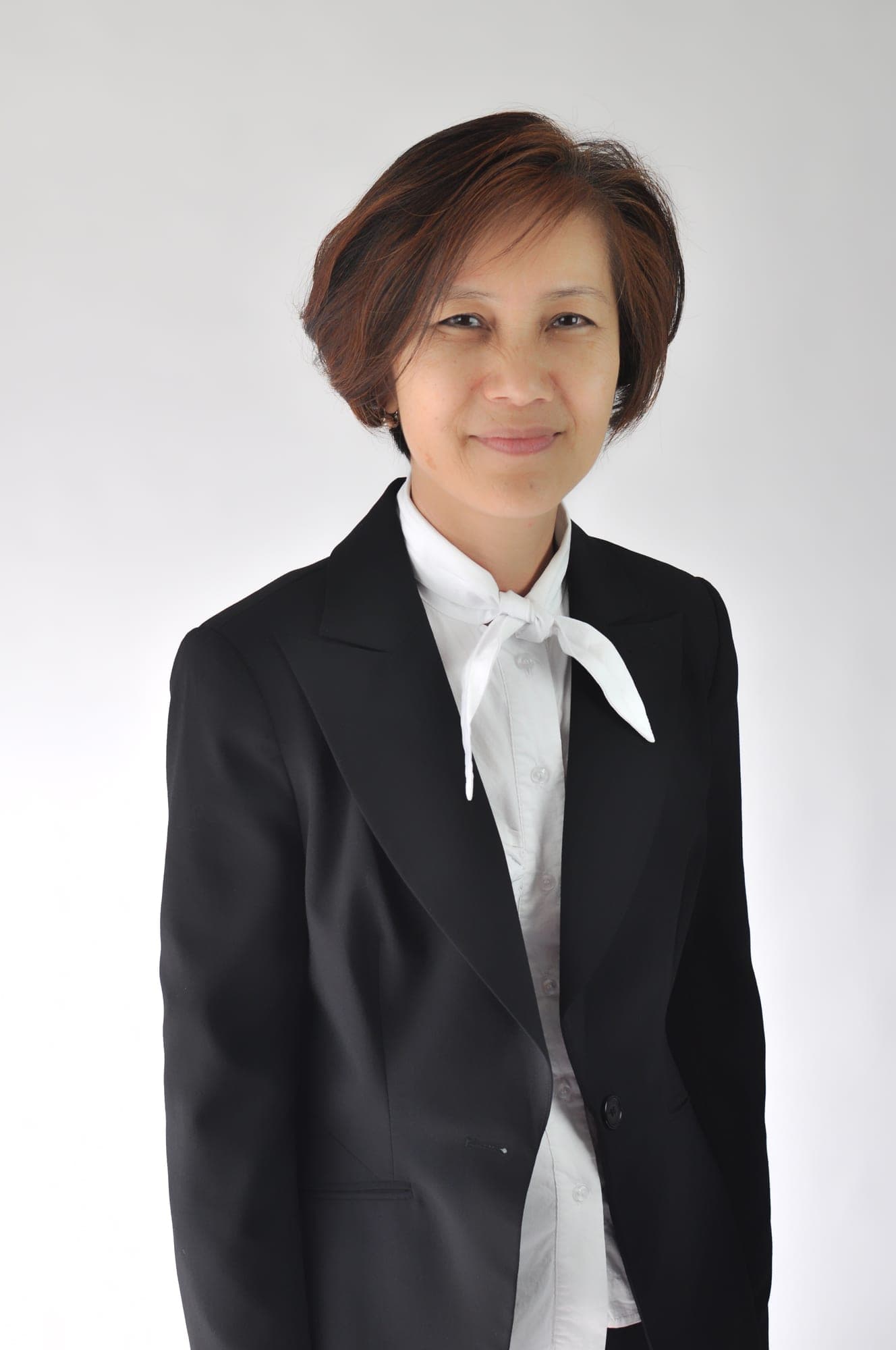 Professional studio headshot in a black blazer on a white background