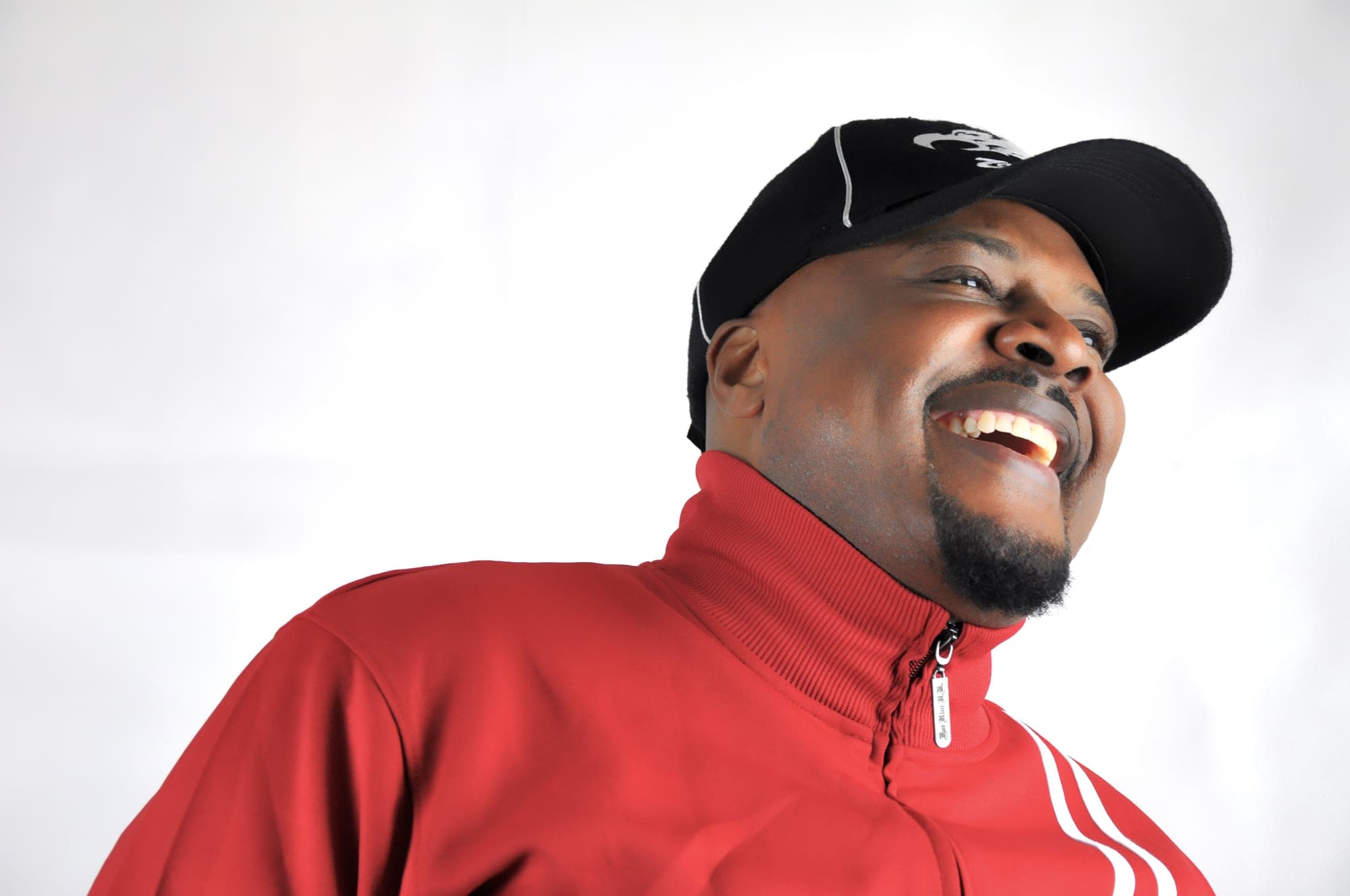 Headshot of a man in a red jacket laughing on a white background