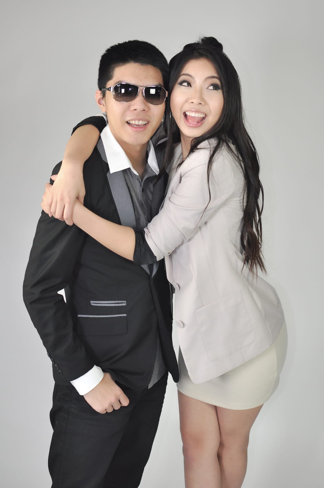 Playful studio portrait of a couple, him in sunglasses