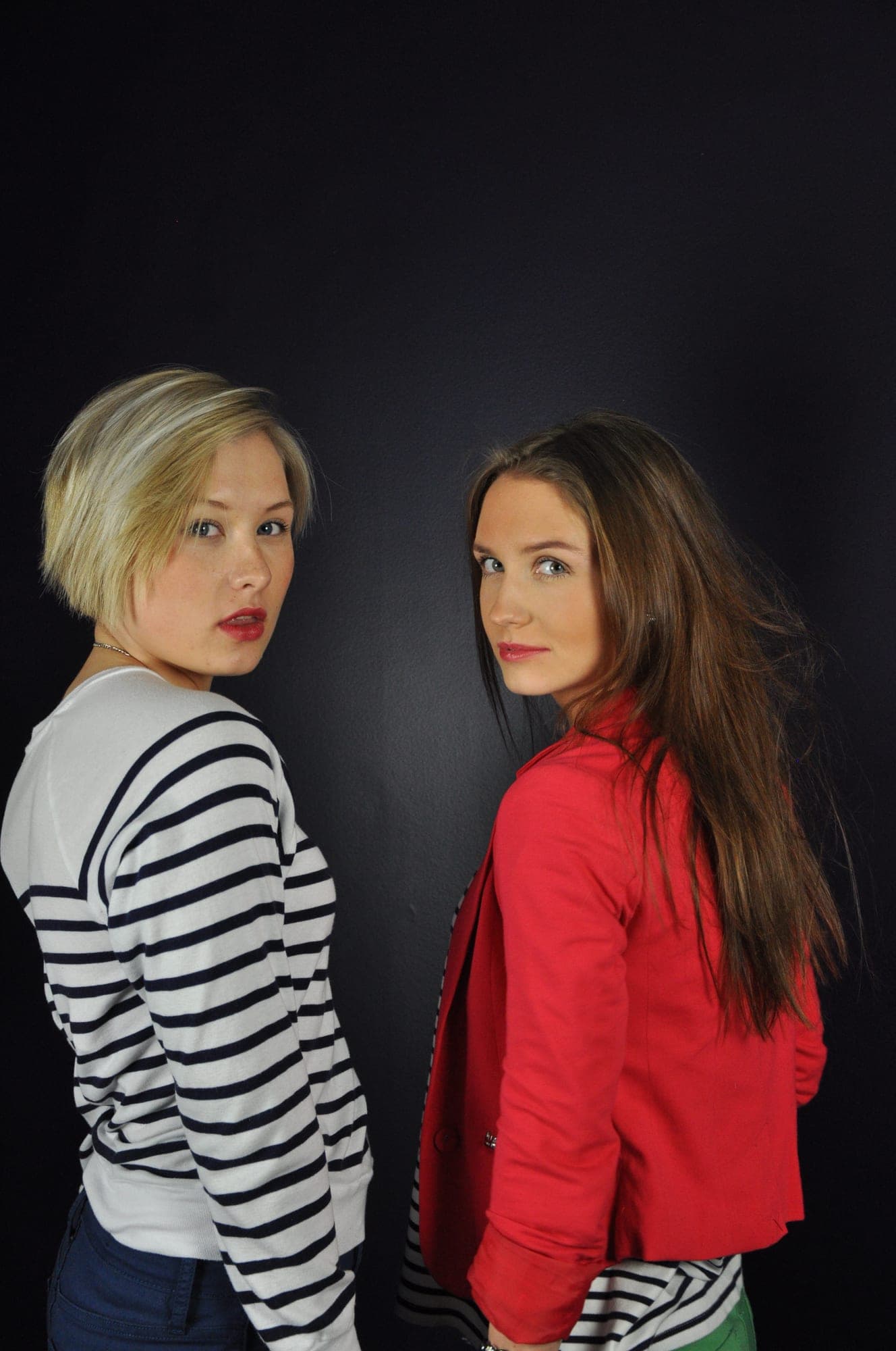 Two women posed back to back in a low-key studio portrait