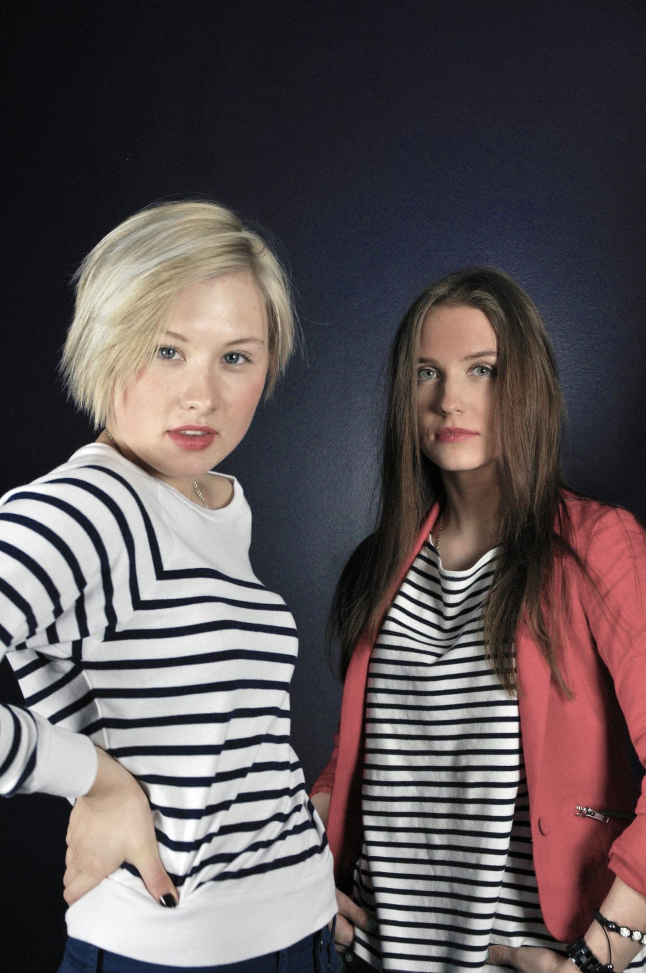 Studio fashion portrait of two women in striped tops and a red blazer