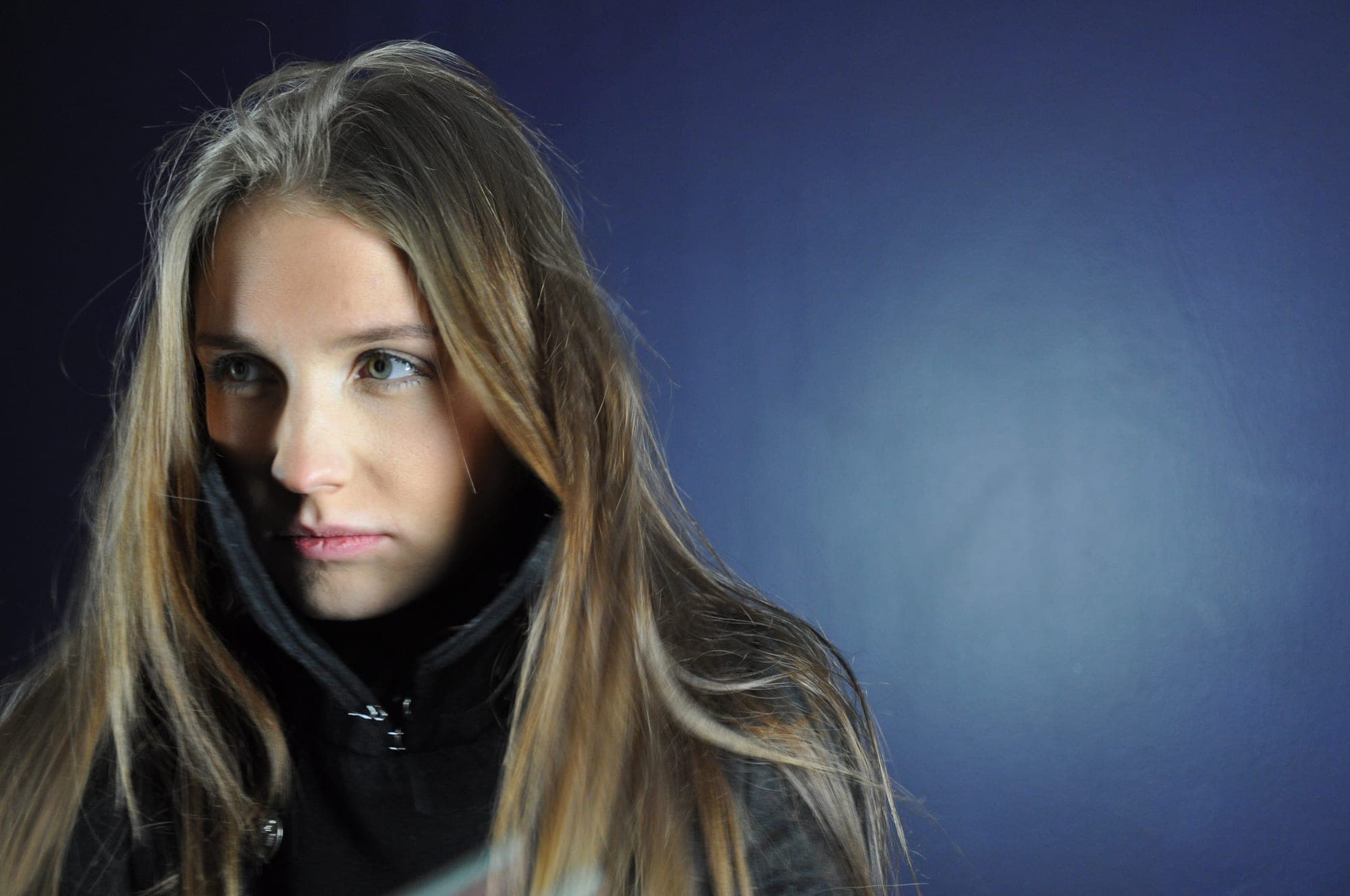 Close portrait of a young woman against a blue studio backdrop