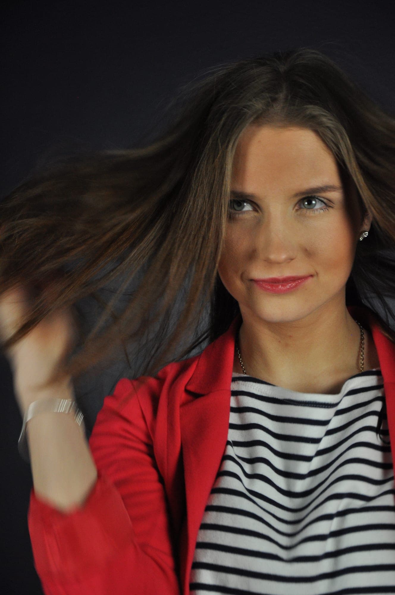 Fashion portrait of a woman with her hair in motion, red jacket