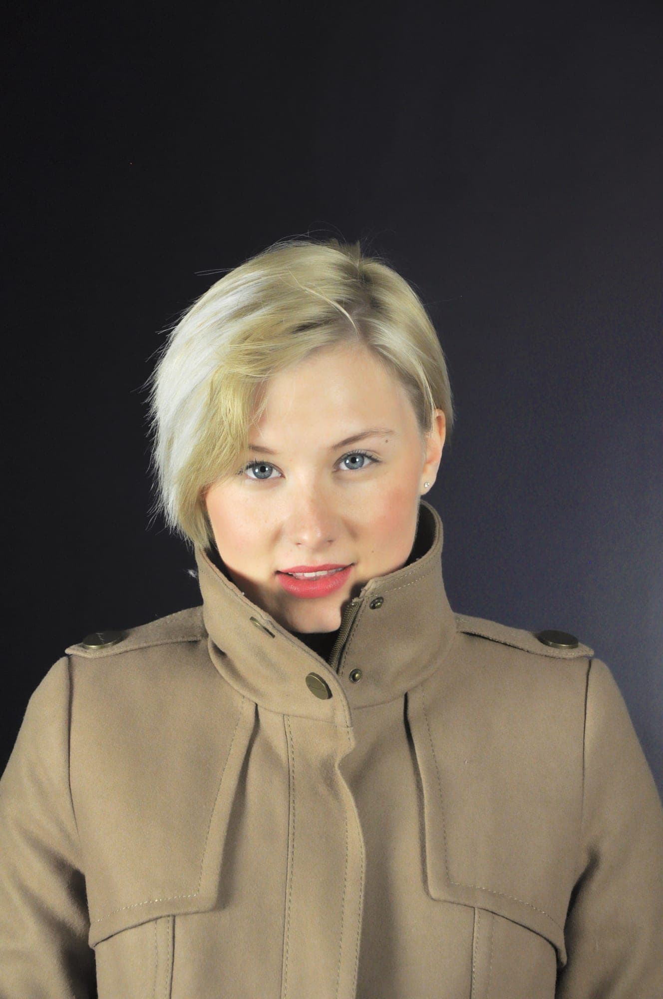 Pensive studio portrait of a woman in a tan coat