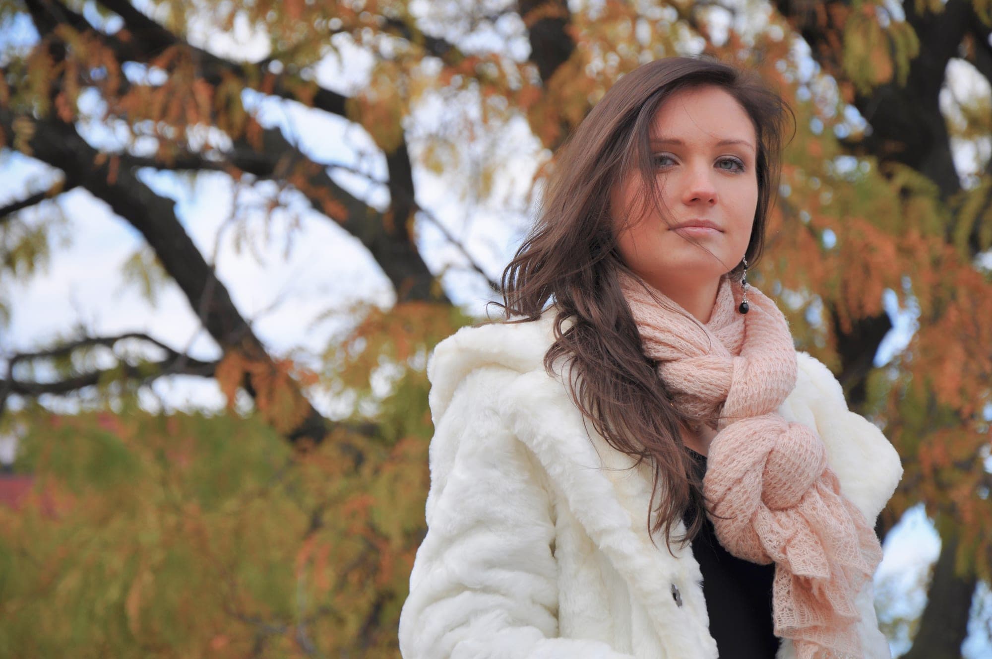 Portrait of a woman in a white coat among autumn trees