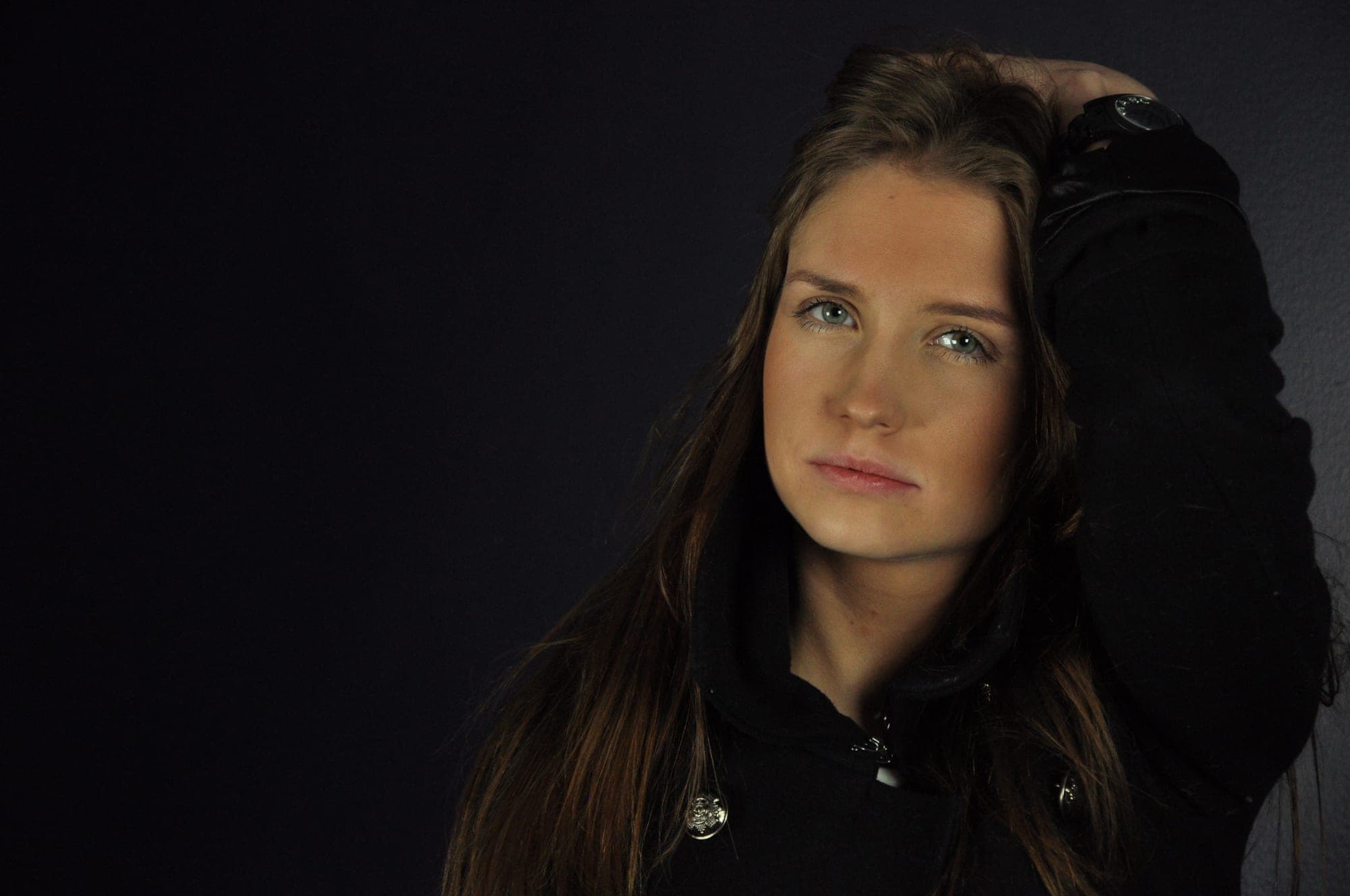 Low-key colour portrait of a young woman against black