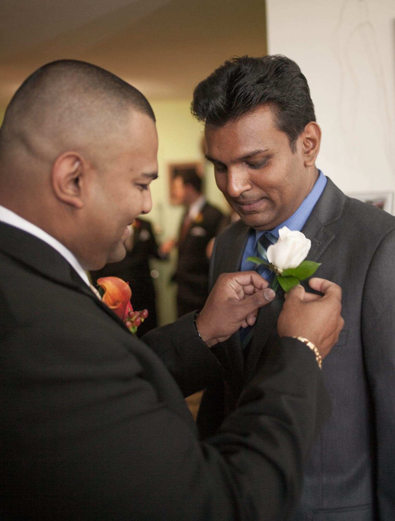Pinning a white rose boutonniere to the groom's lapel