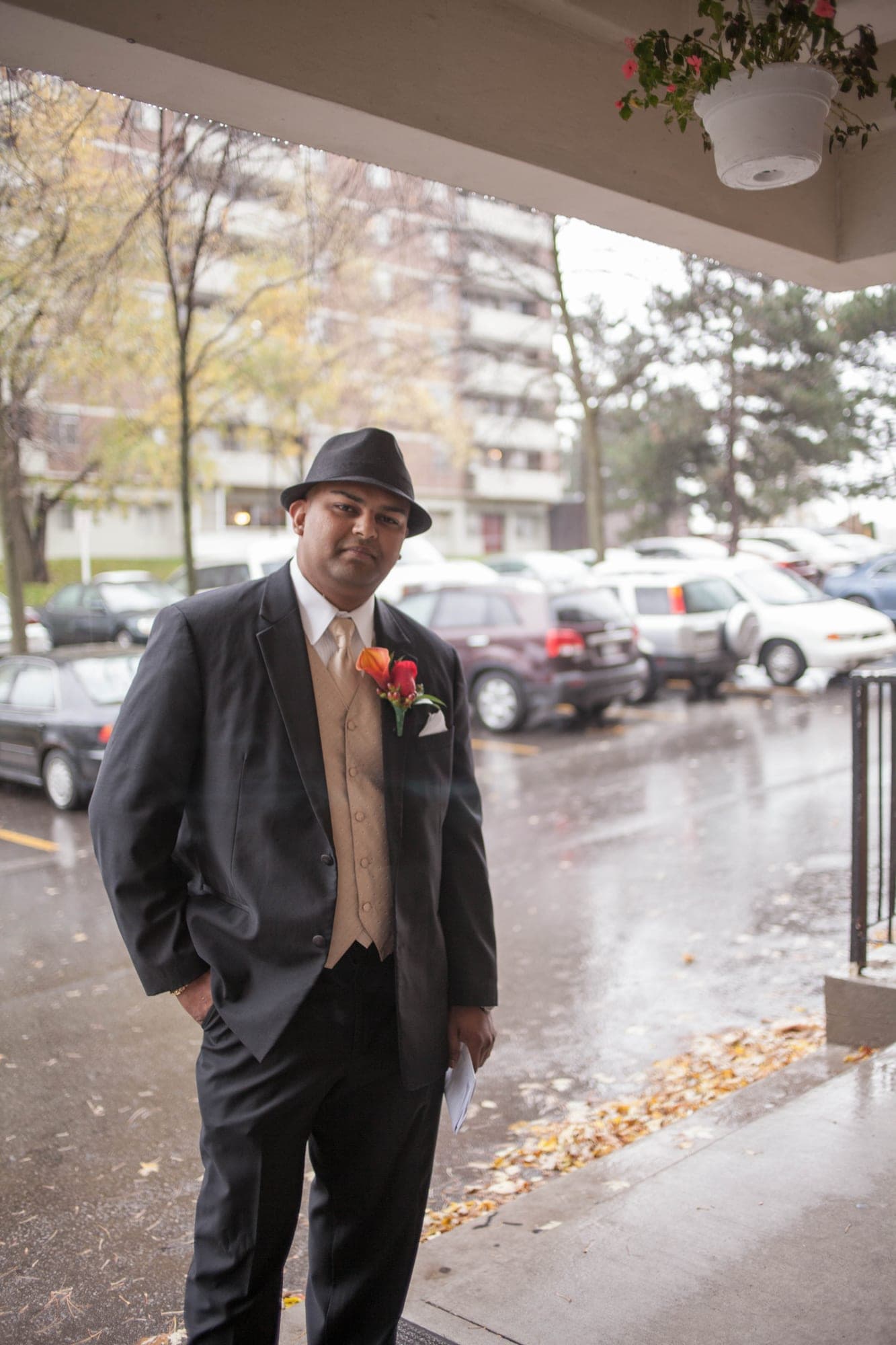 Full-length portrait of a groom in a fedora on a rainy autumn day