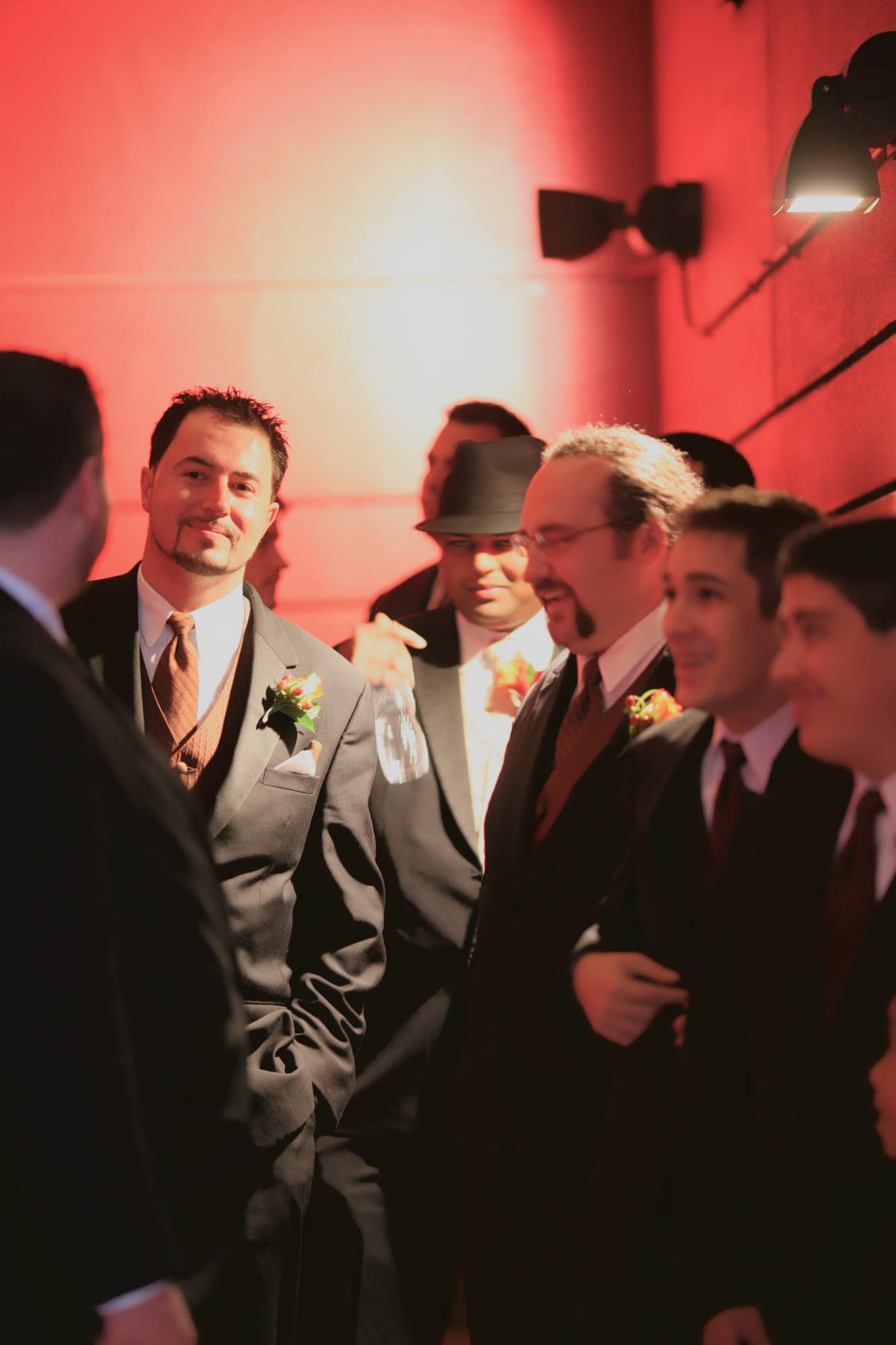 Groom and groomsmen photographed against a dramatic red wall
