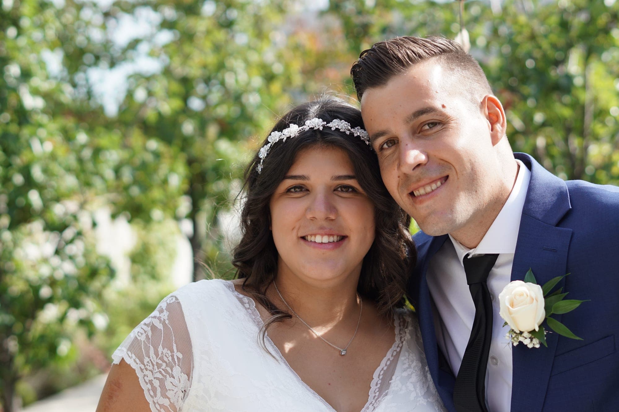 Close-up of newlyweds smiling in front of an ivy-covered wall