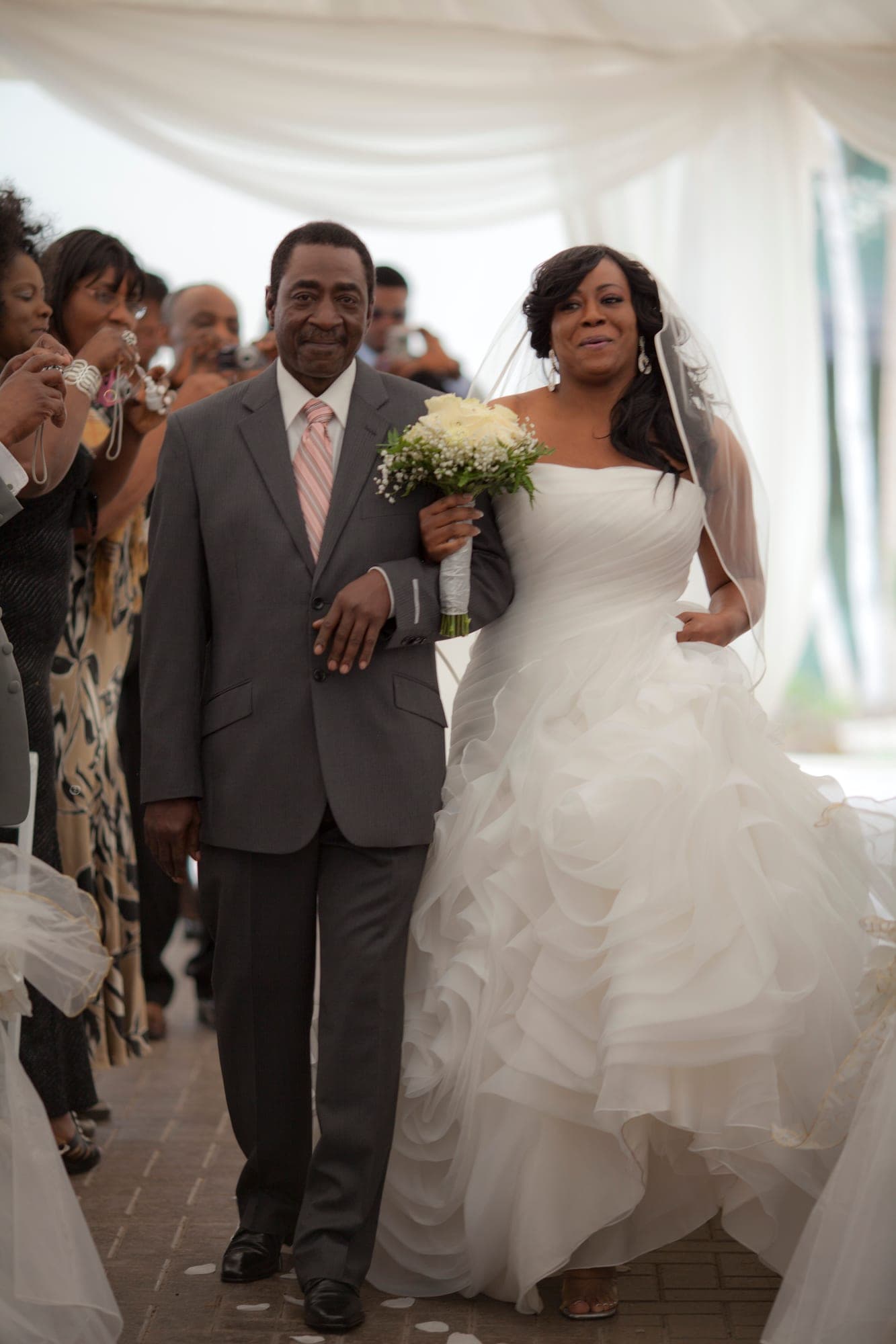 Newlyweds walking back through cheering guests