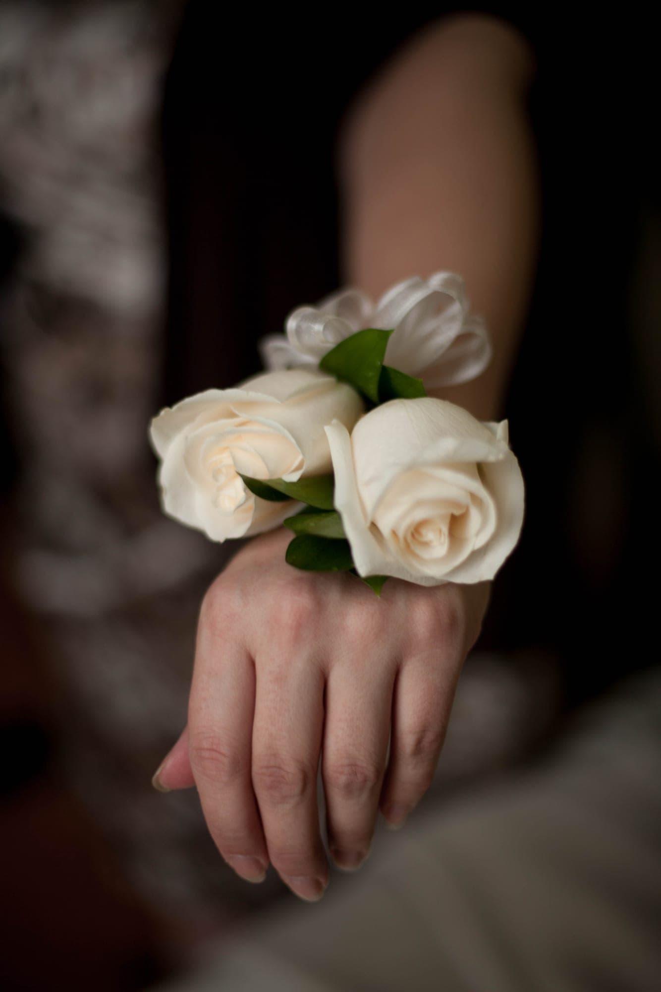 Close-up of a white rose wrist corsage on a guest's hand