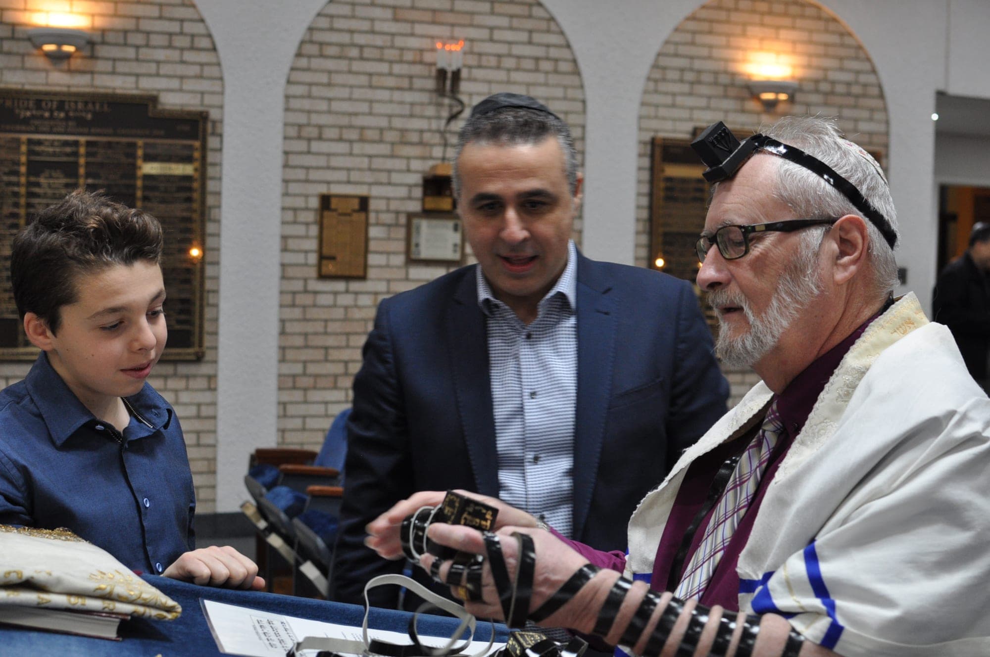 Rabbi helping a bar mitzvah boy lay tefillin