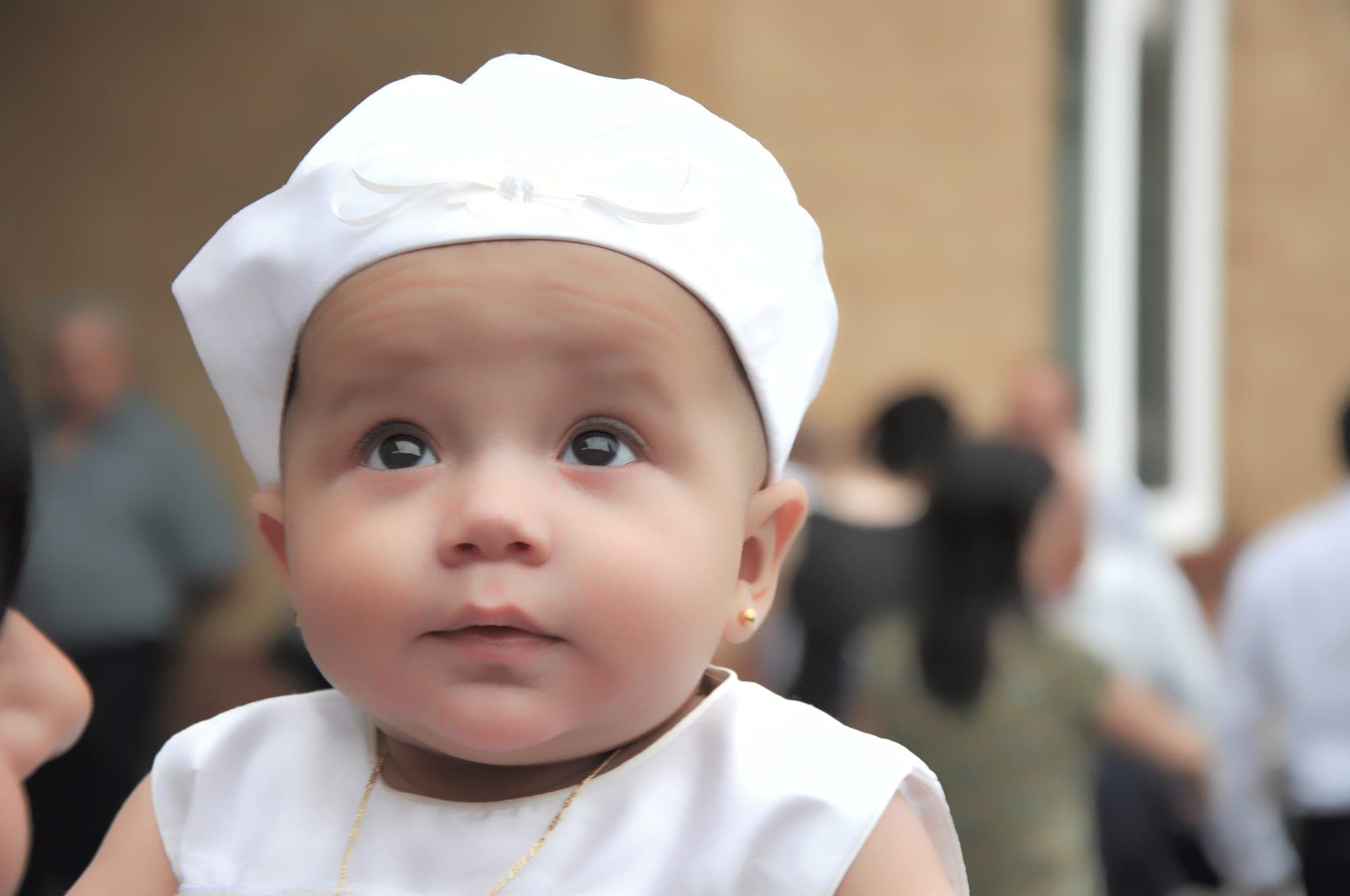 Close-up of a baby in a white christening cap