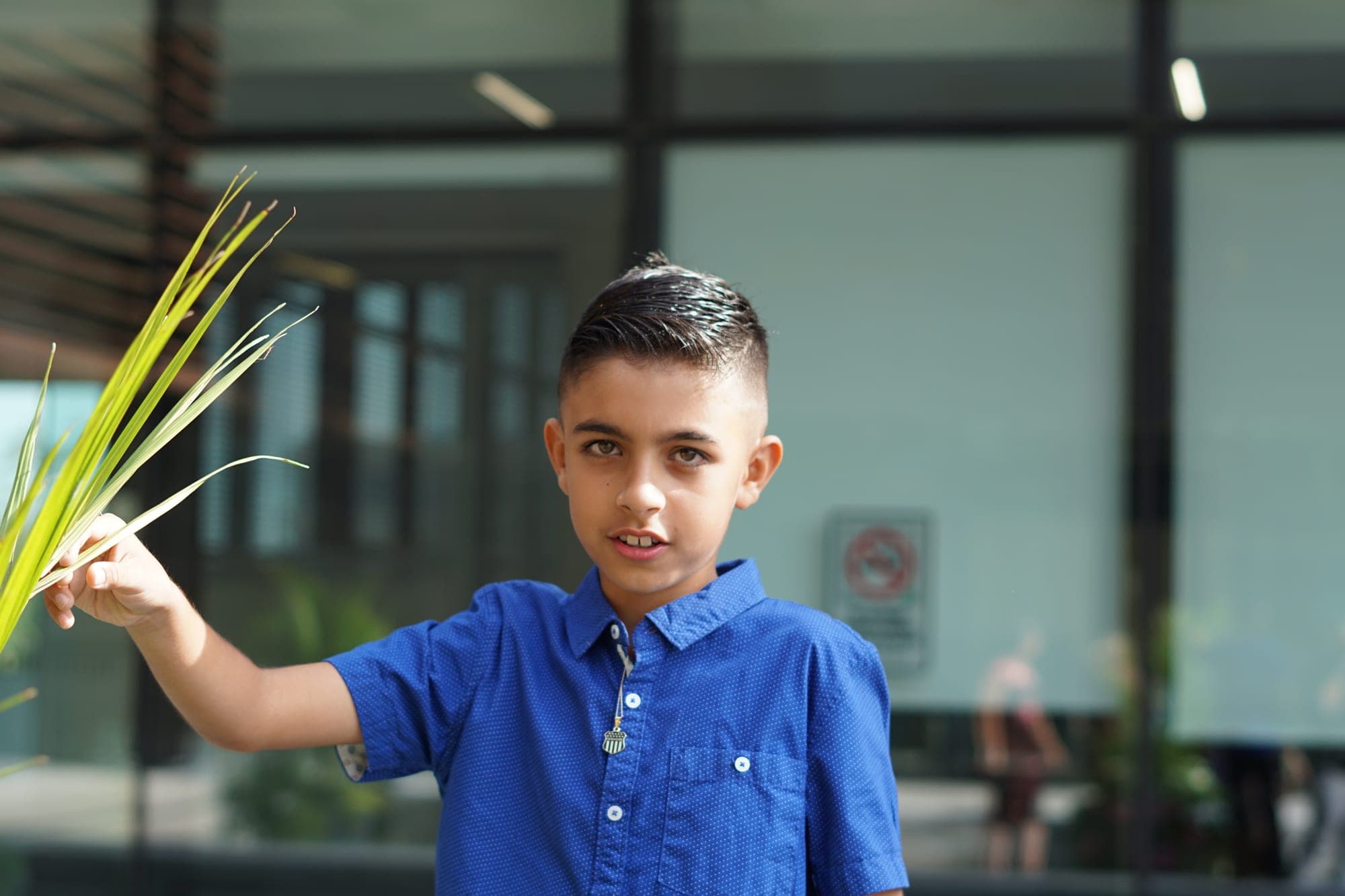 Young wedding guest in a blue shirt holding a blade of grass