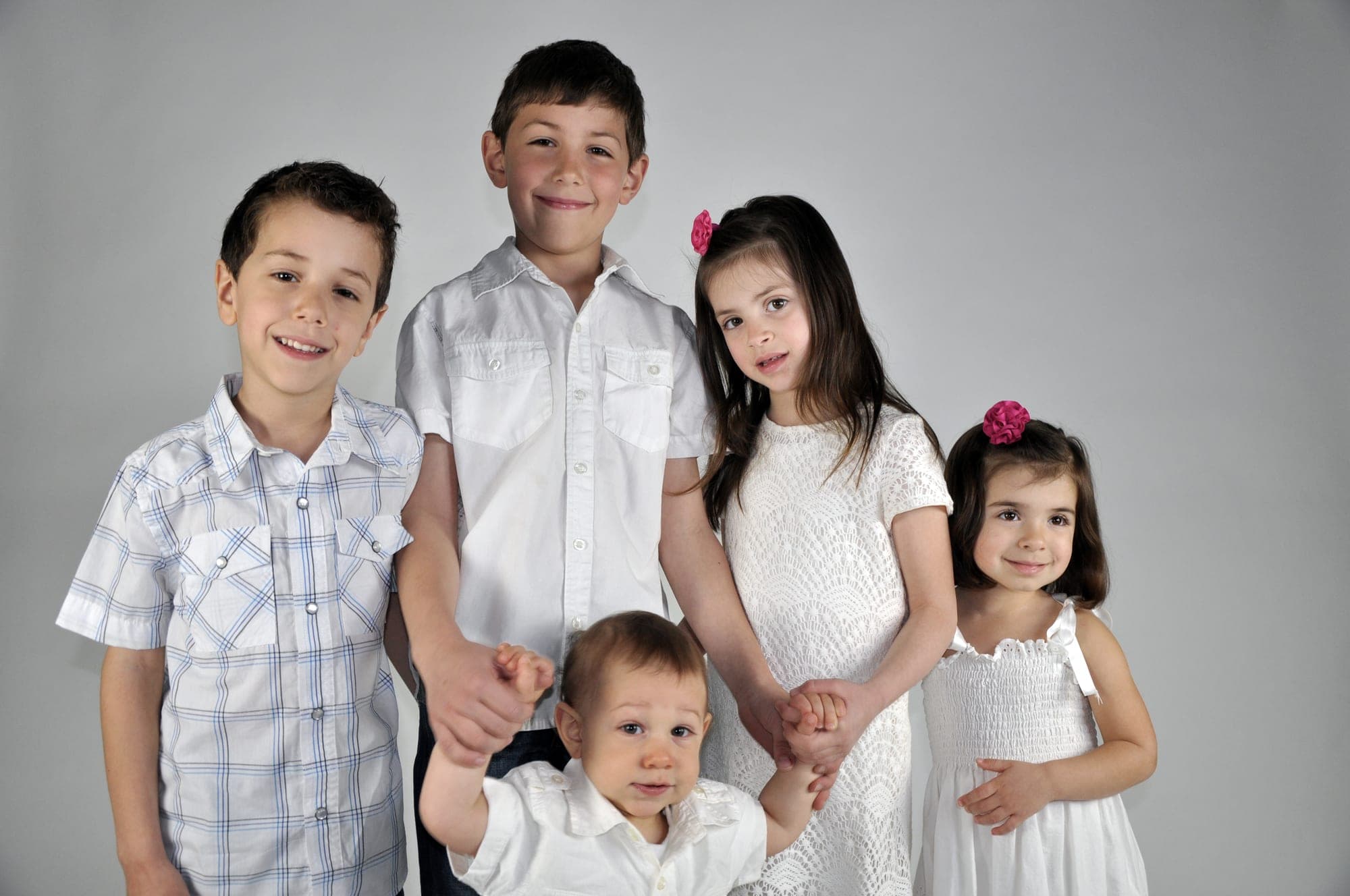 Group studio portrait of five children dressed in white