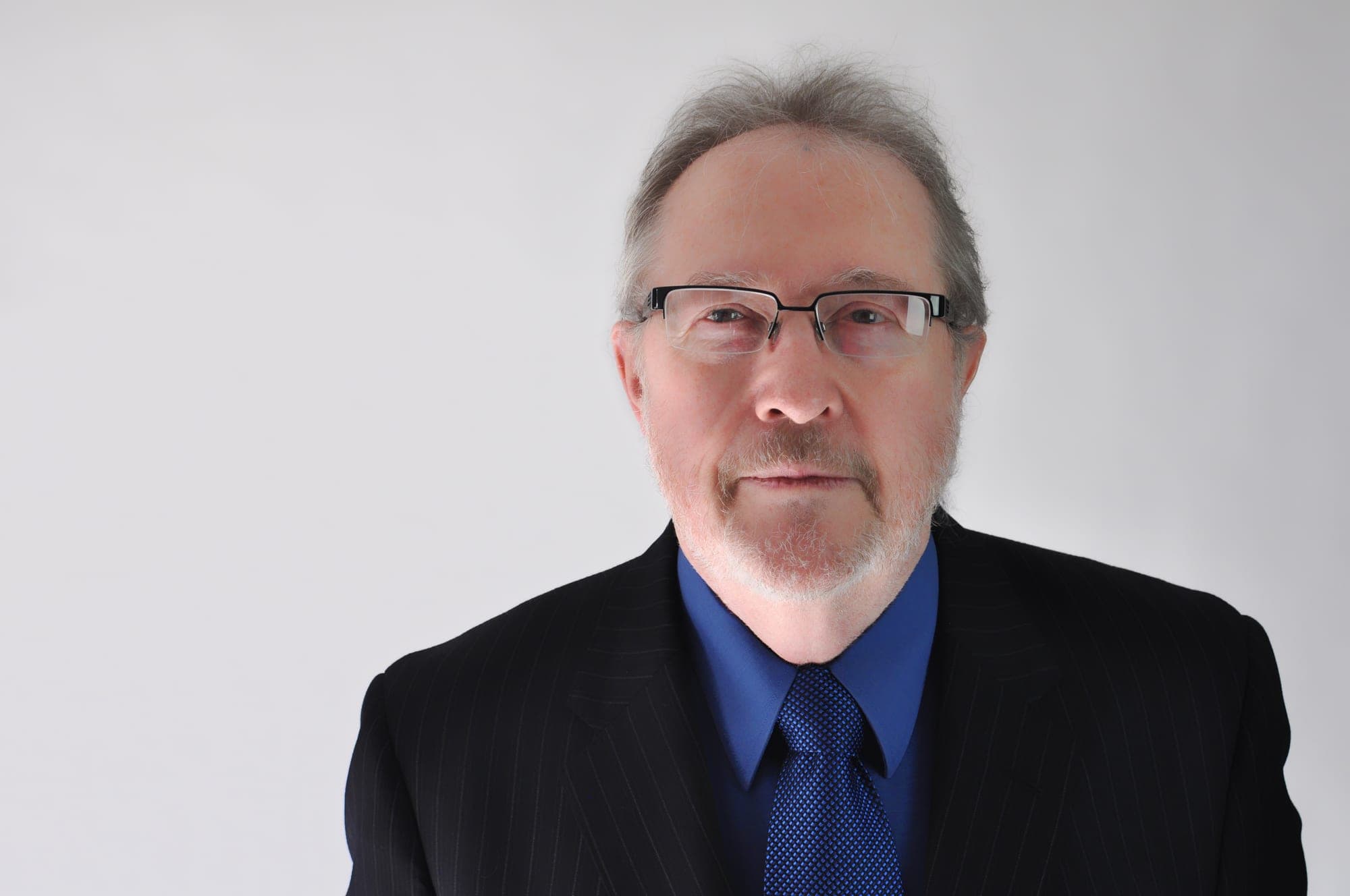 Corporate headshot of a man in a dark suit on a white background