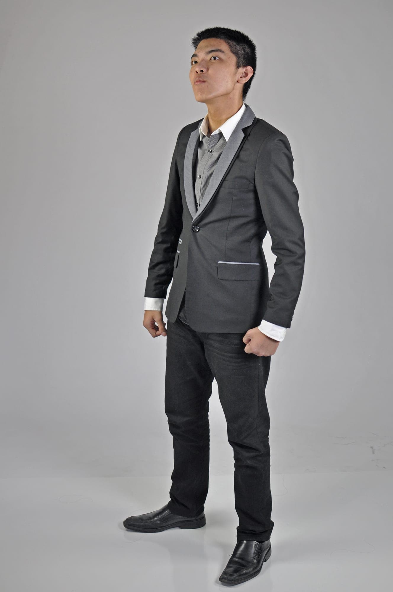 Full-length studio portrait of a teenage boy in a grey suit