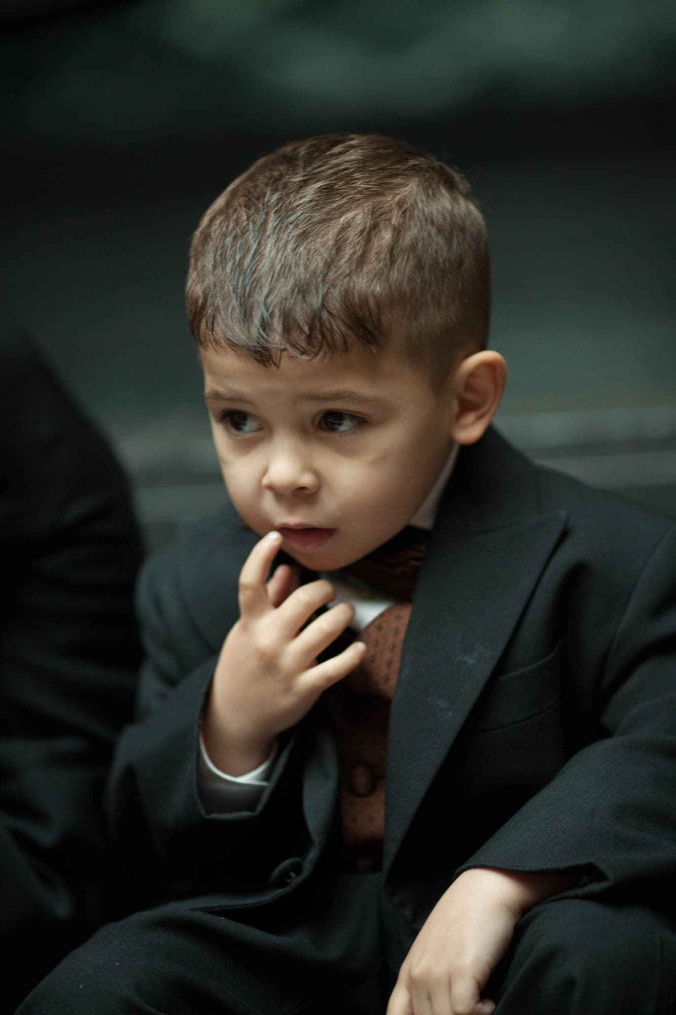 Moody low-key portrait of a young boy in a black suit