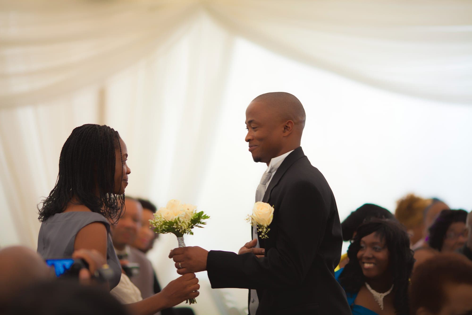 Bride and groom exchanging the bouquet during a marquee ceremony